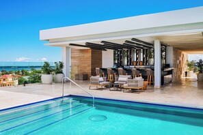 A rooftop pool area with a bar and seating, overlooking a cityscape. - Alaia Belize, Autograph Collection  (San Pedro)