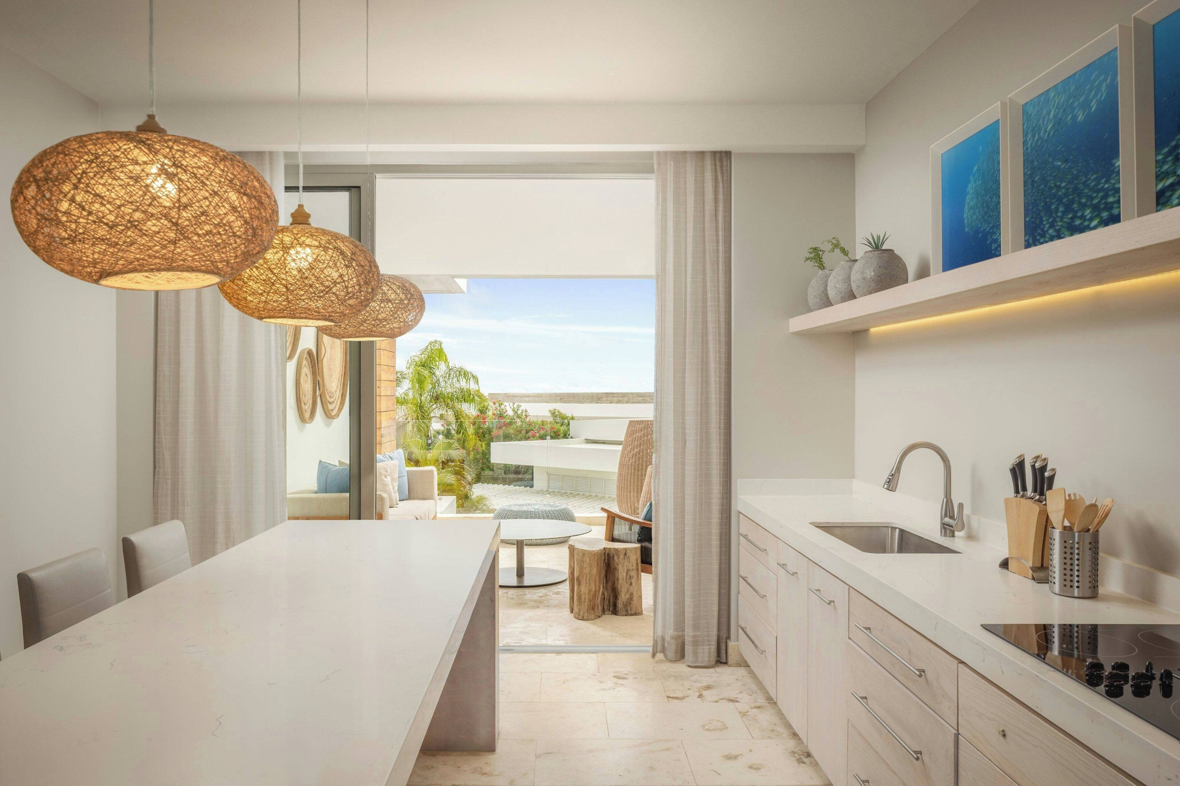 A modern kitchen with a central island, pendant lighting, and a view to an outdoor area.