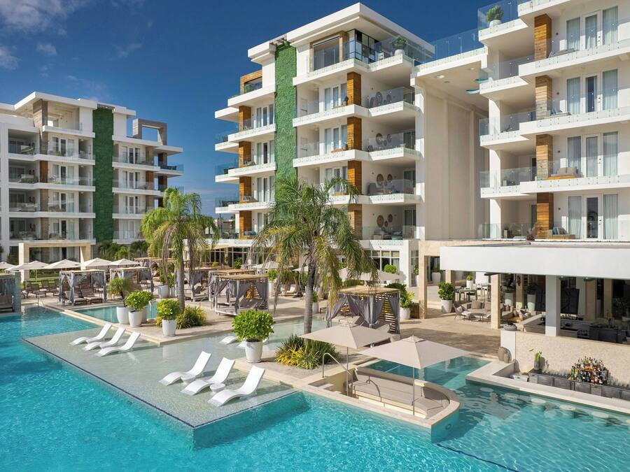 Un hotel moderno con varios balcones, piscina y zonas de estar al aire libre.