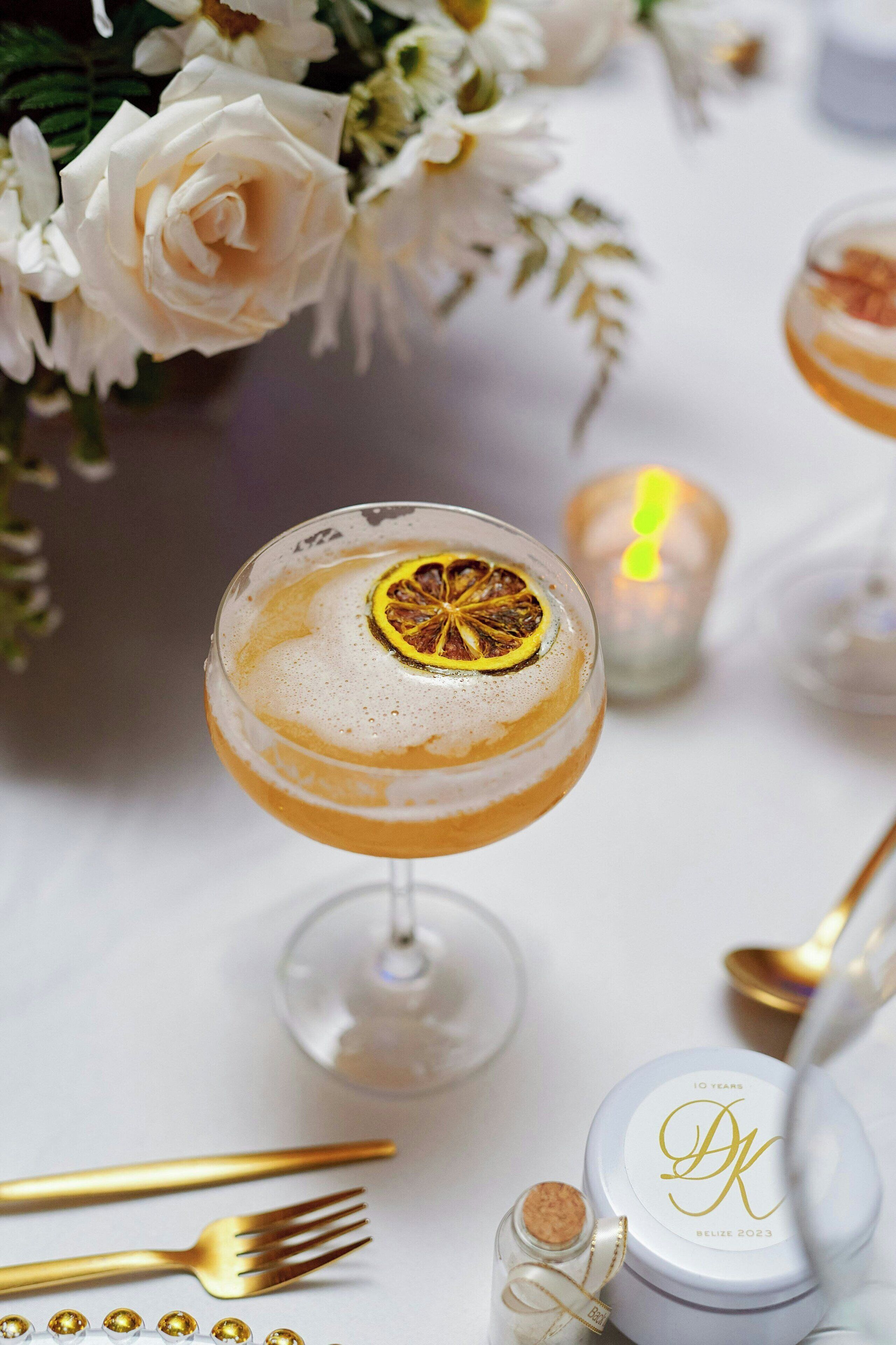 A cocktail glass with a garnish, a candle, and a bottle with a cork.