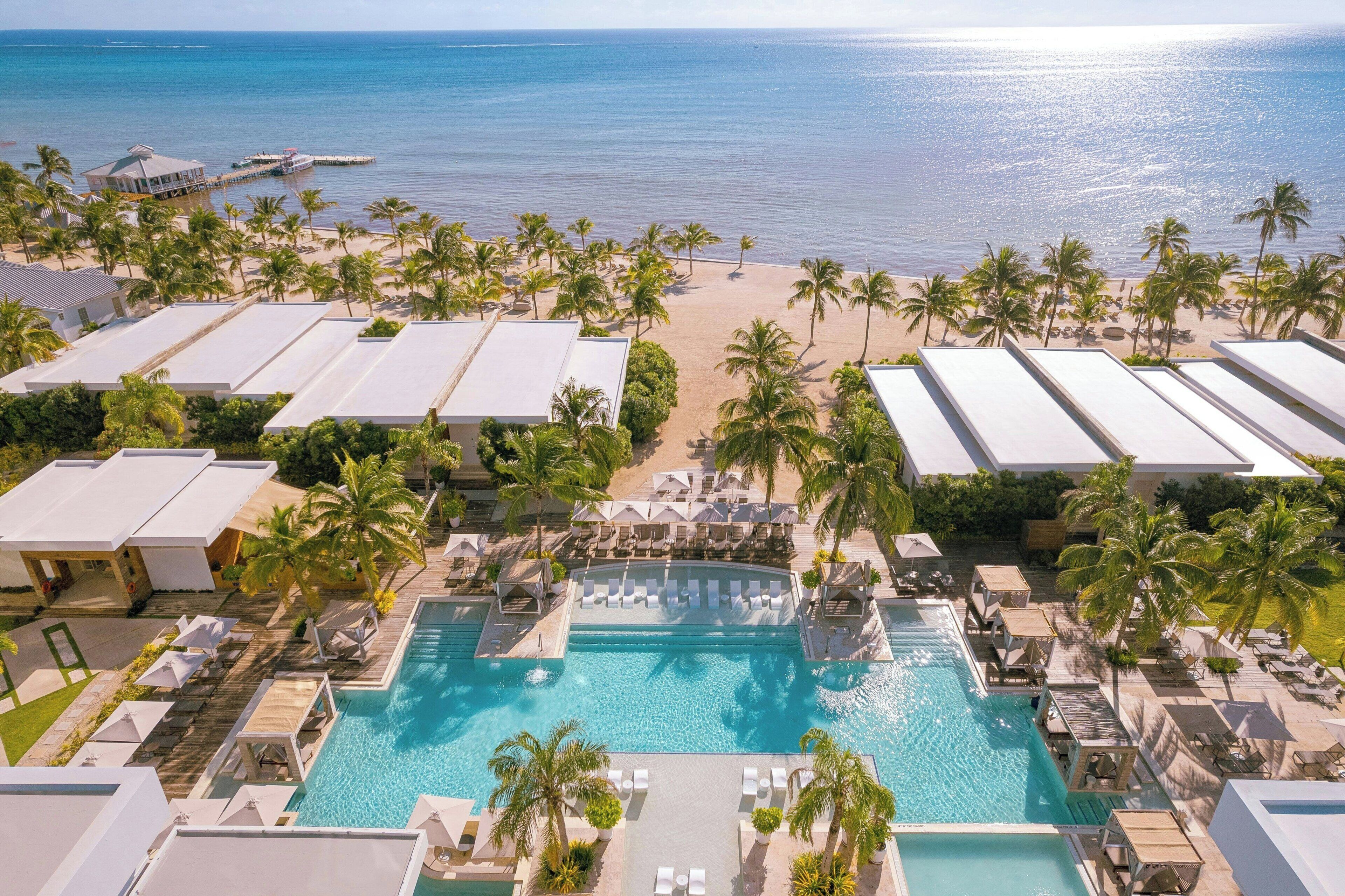 Un resort con una gran piscina, playa y palmeras.