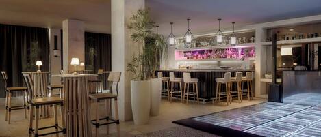 A modern bar area with stools, a bar counter, and a variety of bottles.