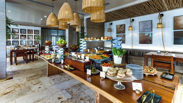 Un montaje tipo bufé con diferentes platillos y un área de comedor con mesas y sillas.