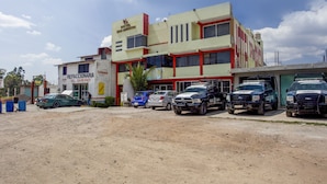 Un hotel de varios pisos y un estacionamiento con varios vehículos.