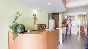 Un área de recepción con mostrador, una puerta de madera, un refrigerador y un refrigerador de Coca-Cola.