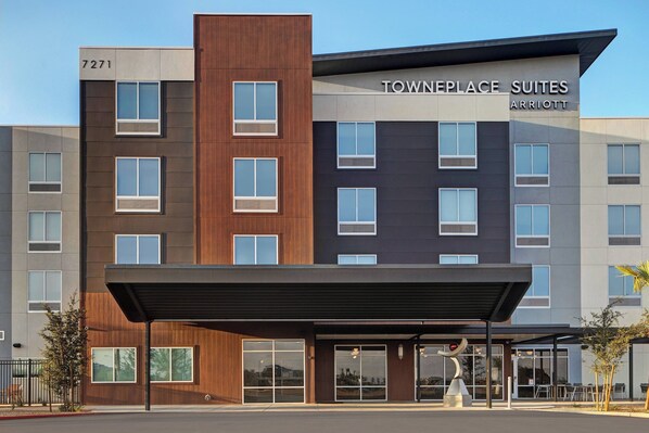 A modern hotel with a Townplace Suites Marriott sign, featuring a mix of wood and metal exterior, large windows, and a covered entrance area.