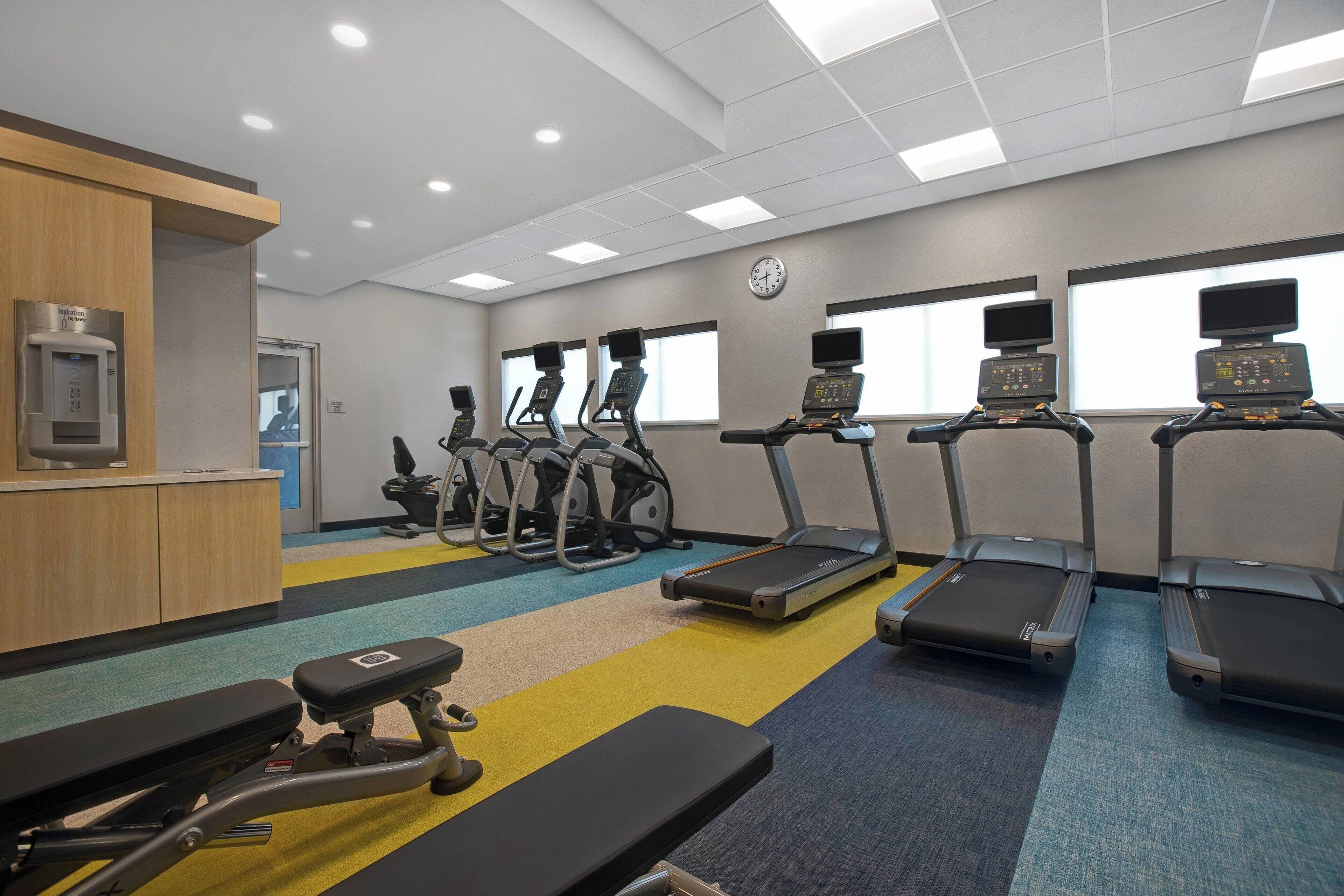 A gym with treadmills, stationary bikes, and a weight bench area.