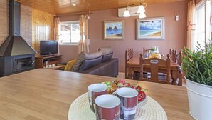 A cozy living room with a fireplace, a television, a sofa, and a dining area with a table set for two. - Vacation home Lorena by Interhome (Deltebre)
