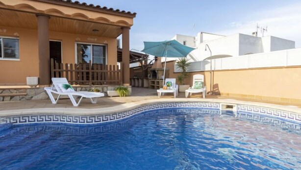 A swimming pool with a geometric tile pattern, surrounded by lounge chairs and a wooden fence. - Vacation home Lorena by Interhome (Deltebre)