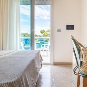 A room with a bed, a view of a pool and chairs outside, and a door leading to the balcony. - Hotel Ettoral (Jesolo)