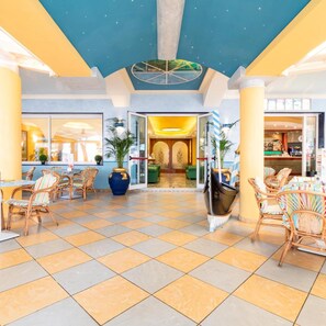 A hotel lobby with a checkered floor, wicker furniture, and a central seating area. - Hotel Ettoral (Jesolo)
