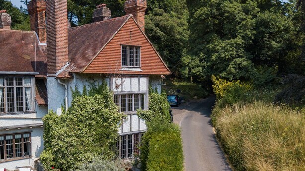 A traditional house with a brick chimney, white walls, and a garden.