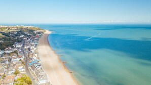 Eine Luftaufnahme einer Küstenstadt mit einem langen Sandstrand, klarem blauen Wasser und einer Mischung aus Wohn- und Geschäftsgebäuden entlang der Küste.