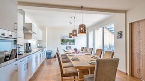 Una cucina moderna con zona pranzo, pavimento in legno e lampade a sospensione.