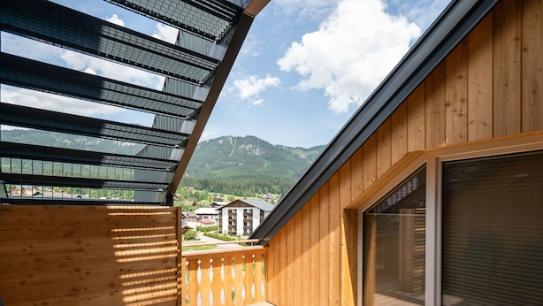 Un pontile in legno con vista su una montagna e degli edifici.