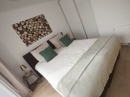 Ein Schlafzimmer mit Bett, Kissen, Nachttisch, Lampe und einer Wanddekoration.