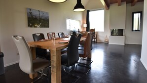 A dining area with a wooden table and chairs, pendant lights, and a painting on the wall. - Traditional Villa in Tzummarum near Sea (Tzummarum)