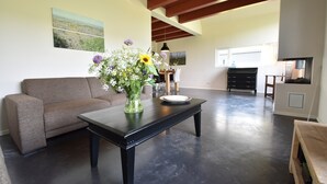 A living room with a sofa, a coffee table with a vase of flowers, and a dining area with a table and chairs. - Traditional Villa in Tzummarum near Sea (Tzummarum)