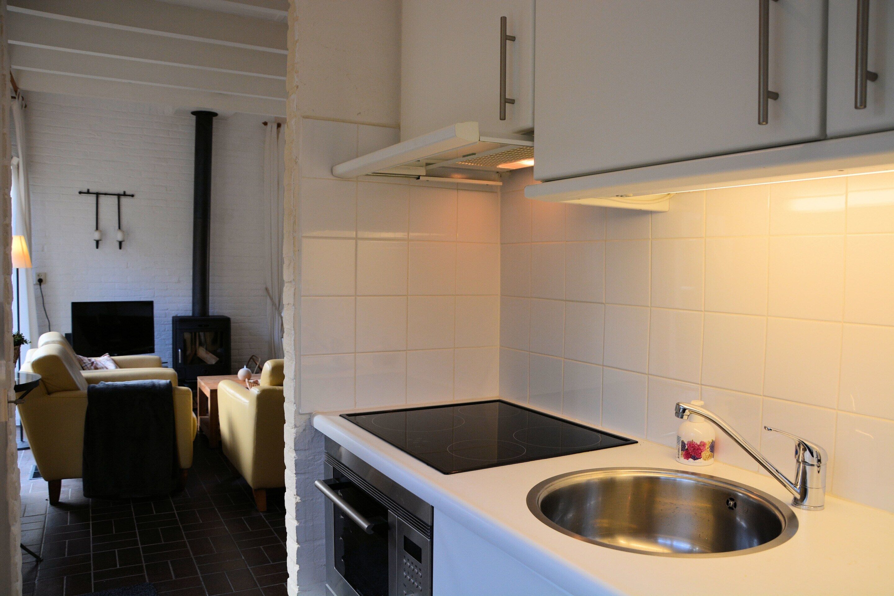 A modern kitchen with a built-in stove, a sink, and white cabinetry.
