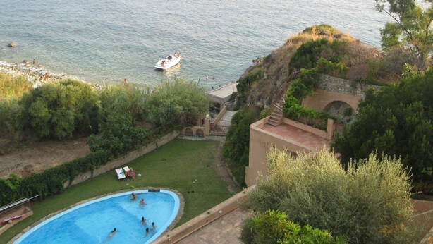 A swimming pool with people, a boat on the water, and a view of the sea. - Mansion in Capo Vaticano by the Sea (Ricadi)