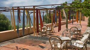 An outdoor seating area with wicker chairs and a pergola with hanging fabrics. - Mansion in Capo Vaticano by the Sea (Ricadi)