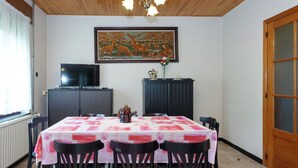 A dining area with a table set for four, a television on a cabinet, and a painting on the wall. - Quaint Holiday Home With Fenced Garden in Manhay (Manhay)