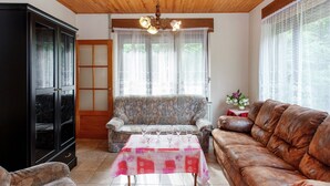 A living room with a sofa, a brown leather couch, a table with glasses, and a cabinet. - Quaint Holiday Home With Fenced Garden in Manhay (Manhay)