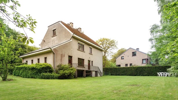 A two-story house with a large front lawn, a staircase leading to a balcony, and a neighboring building. - Quaint Holiday Home With Fenced Garden in Manhay (Manhay)