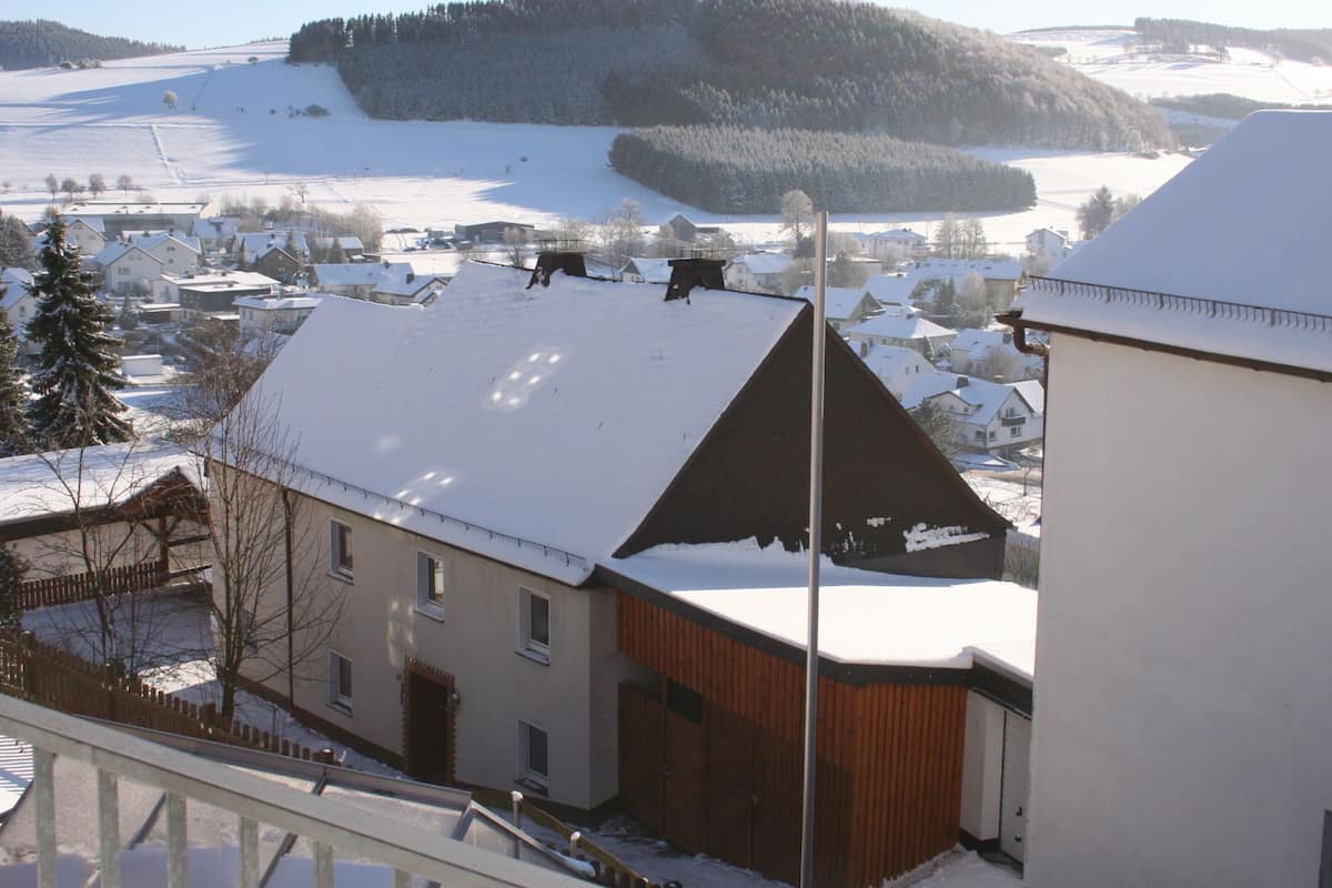 Um edifício com telhado inclinado e cerca de madeira em uma paisagem coberta de neve.