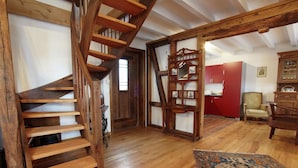 A spacious room with a wooden staircase, a red wall, a patterned rug, and a chair. - Nostalgic Apartment in the Beautiful Eifel Region (Schleiden)