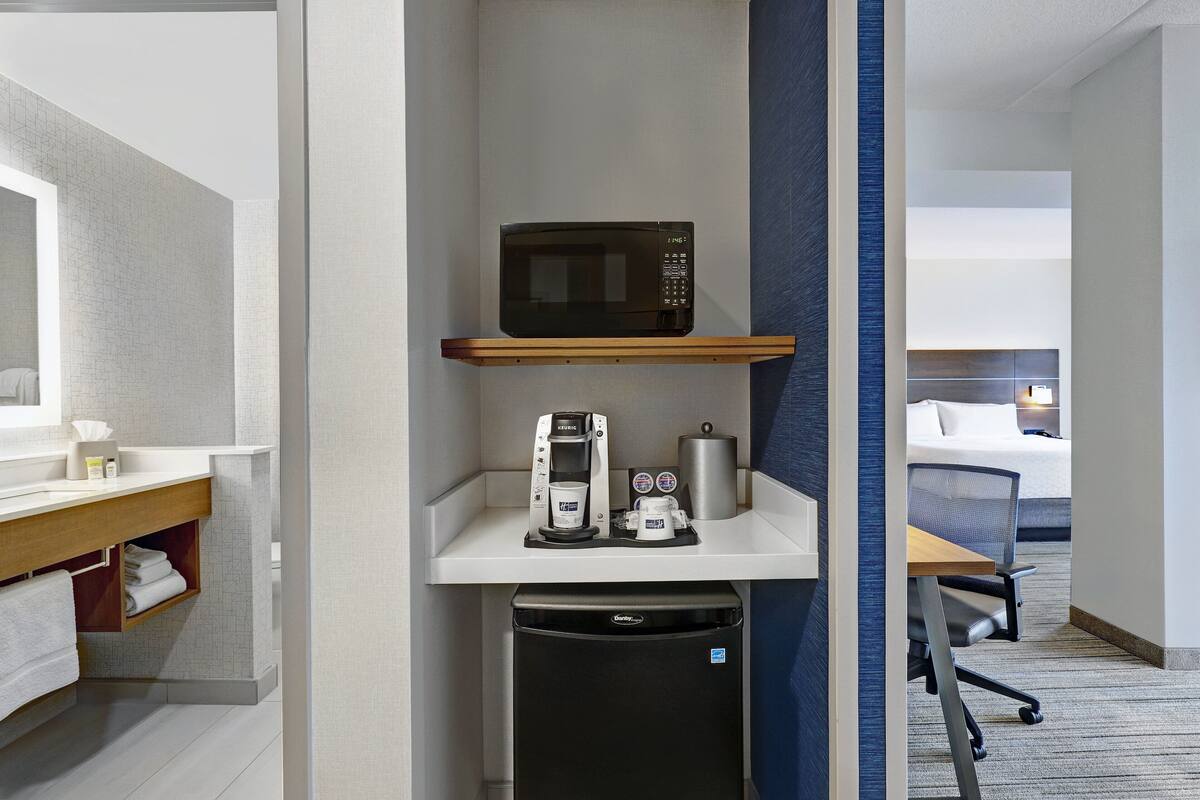 Une chambre d’hôtel compacte dotée d’une kitchenette, comprenant un four à micro-ondes, une machine à café et un mini-réfrigérateur.
