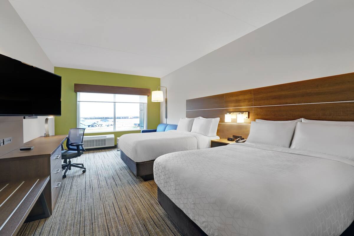 Une chambre d’hôtel avec deux lits, un bureau, une chaise, une télévision et une fenêtre donnant sur un beau paysage.