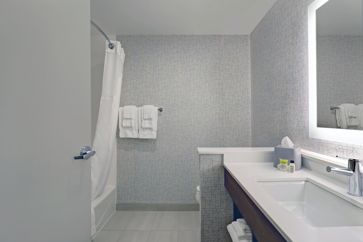 A modern bathroom with a shower, a sink, and a mirror.