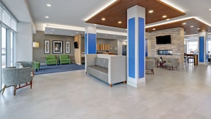 A spacious lobby with a central seating area, a stone fireplace, and a television mounted on the wall. - Holiday Inn Express & Suites Port Elgin by IHG (Saugeen Shores)