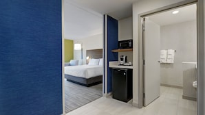 A hotel room with a bed, a small kitchenette, a bathroom, and a blue accent wall. - Holiday Inn Express & Suites Port Elgin by IHG (Saugeen Shores)