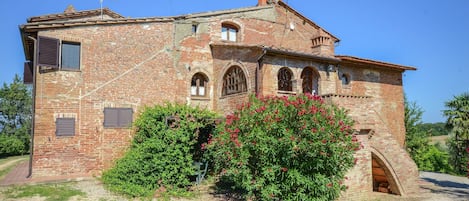 A rustic brick building with arched windows and a small entrance.