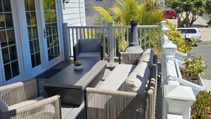 A covered outdoor seating area with wicker furniture, a table, and a view of the street.