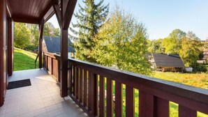 A covered porch with a view of a green landscape and a house in the background. - Holiday Hill 33 by Interhome (Cerny Dul/Cista)