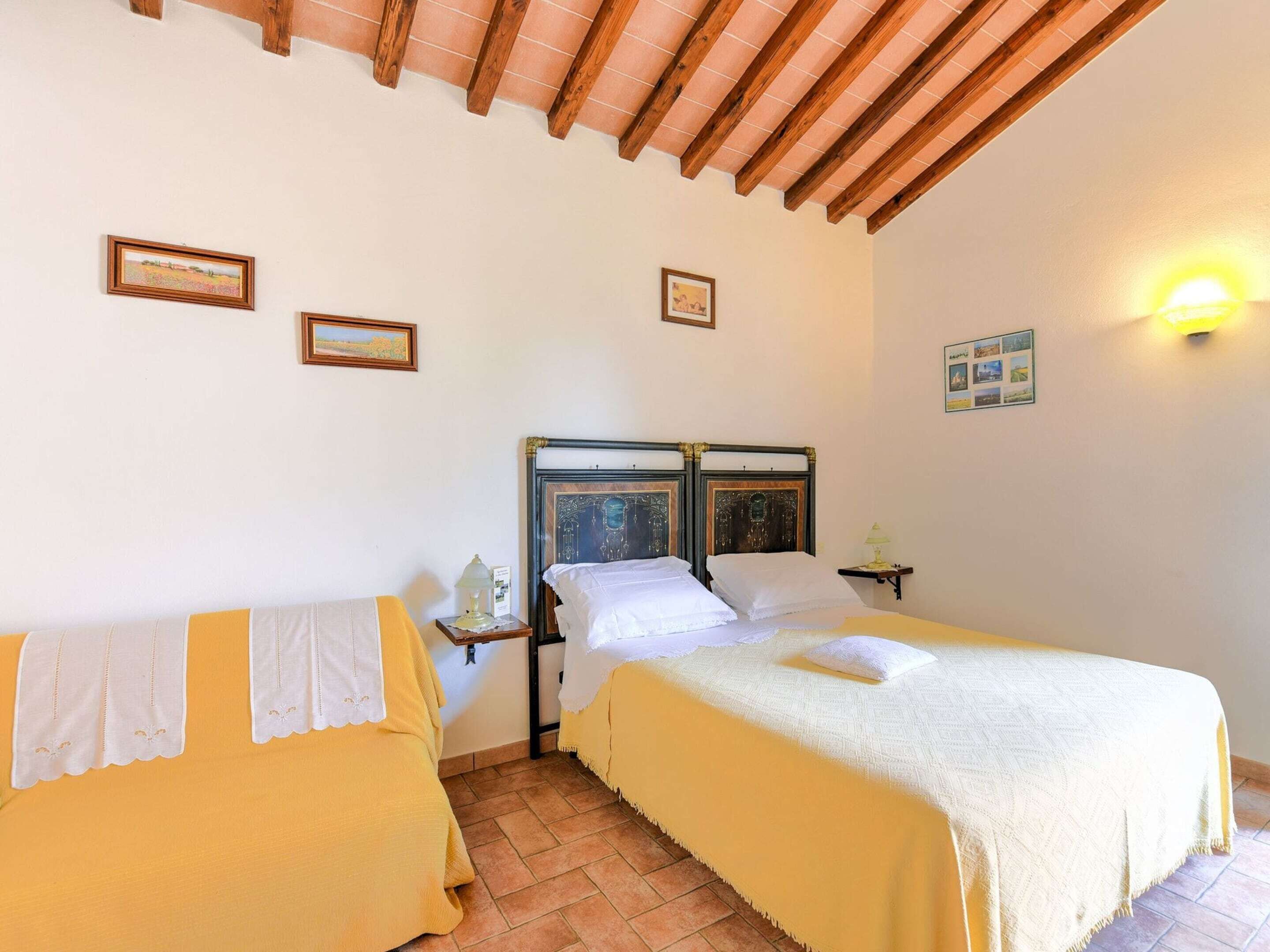 Una habitació amb dos llits, sostre de fusta i una làmpada penjada a la paret.