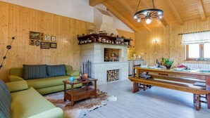Un accogliente soggiorno con soffitto in legno, camino, zona pranzo e divano.