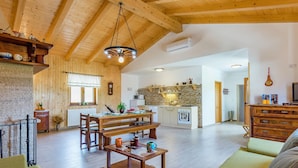 Un'ampia zona giorno con soffitto in legno, un tavolo da pranzo apparecchiato con piatti e bicchieri, un divano e una pelliccia decorativa.