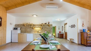 Un'ampia cucina con soffitto in legno, un'area pranzo con tavolo imbandito per quattro persone e vista su un soggiorno.