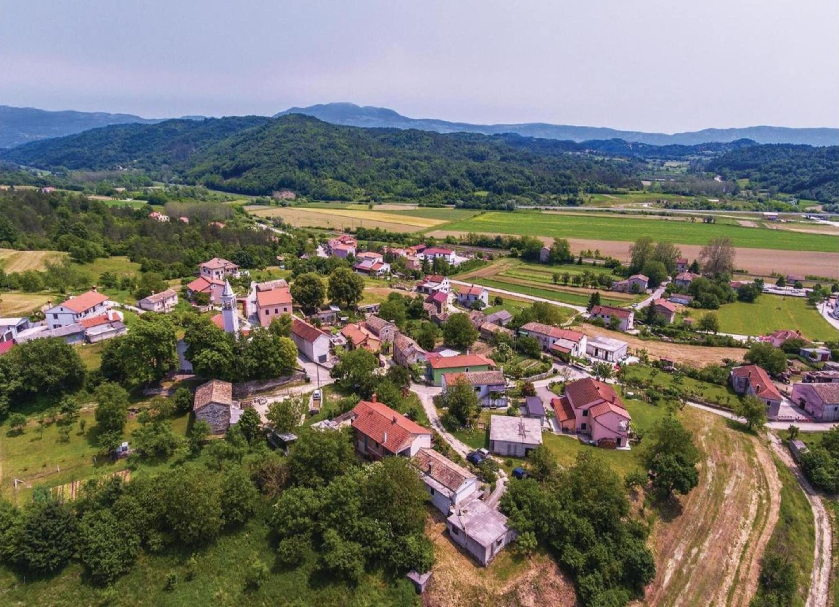 Vista aérea de un pueblo con casas, una iglesia y campos circundantes.
