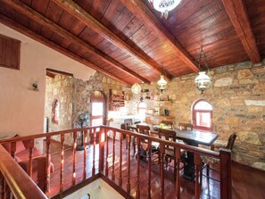 Cozy dining area with a wooden table and chairs, stone wall, and exposed wooden beams.