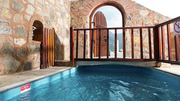 A stone building with a pool and a wooden gate. - Traditional Apartment in Elounda (Agios Nikolaos)