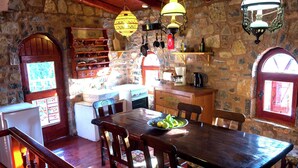 A rustic kitchen with stone walls, wooden furniture, and hanging light fixtures. - Traditional Apartment in Elounda (Agios Nikolaos)