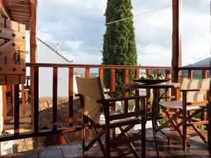 Relax on the traditional deck with a serene view of the lush green tree and distant landscape.