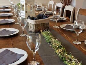 A dining table set with plates, napkins, and wine glasses, with a decorative garland and a basket of napkins. - Holiday Home in Jupille Near Forest Trails (Rendeux)