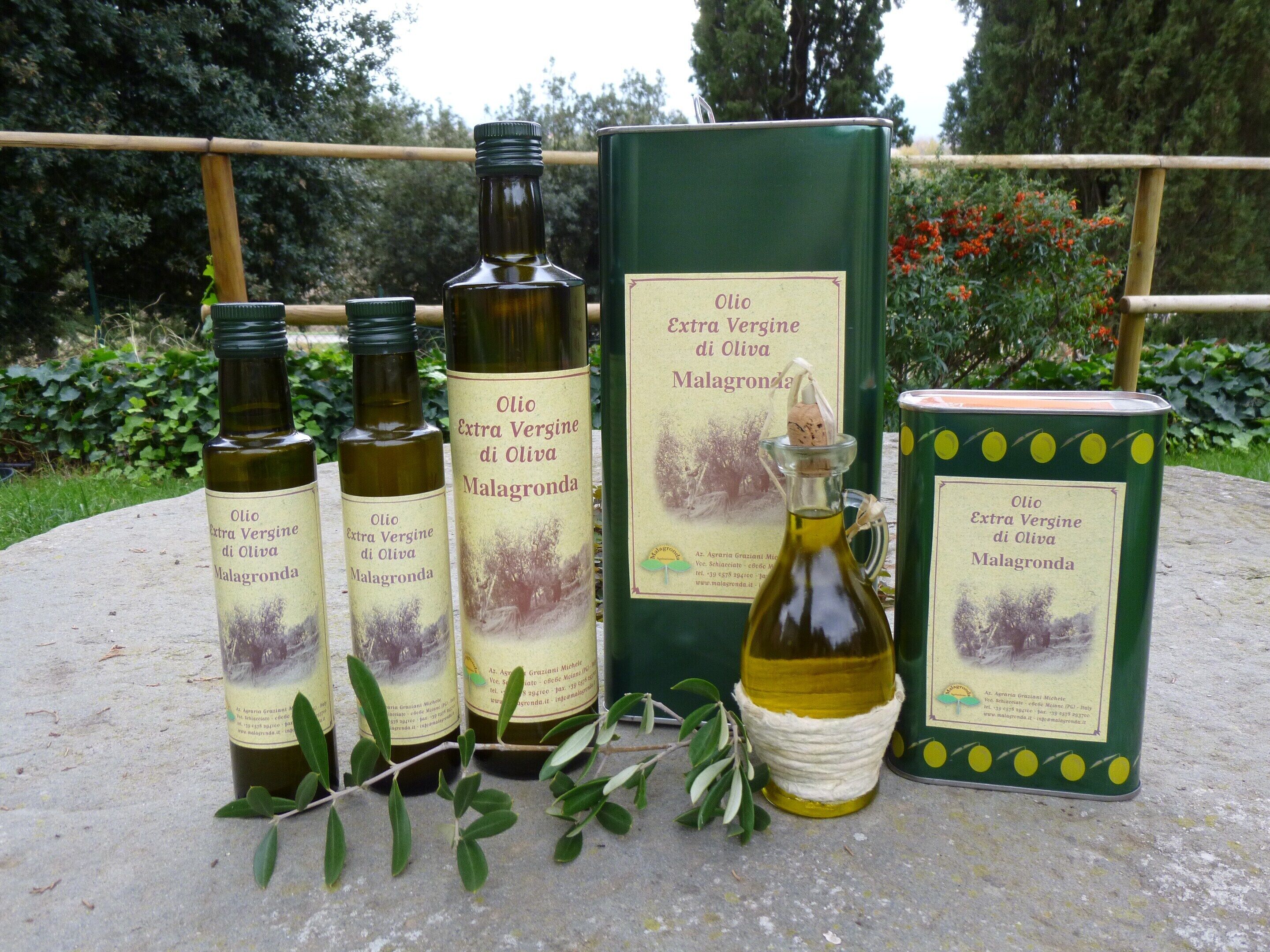 Three bottles of extra virgin olive oil, a green box, and a small bottle with a cork.