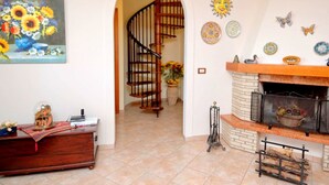 Un salon avec une cheminée, un escalier en bois et un tableau représentant des fleurs.